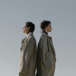 Dwie kobiety w modnych trenczach stoją tyłem do siebie na zewnątrz