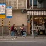 Dwoje dorosłych je uliczne jedzenie przy stoliku w Tajpej