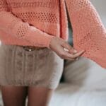 Kobieta w ażurowym swetrze i dzianinowej spódnicy jako warstwa pod płaszcz