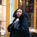 Kobieta w czarnym futrzanym płaszczu w przytulnej paryskiej księgarni