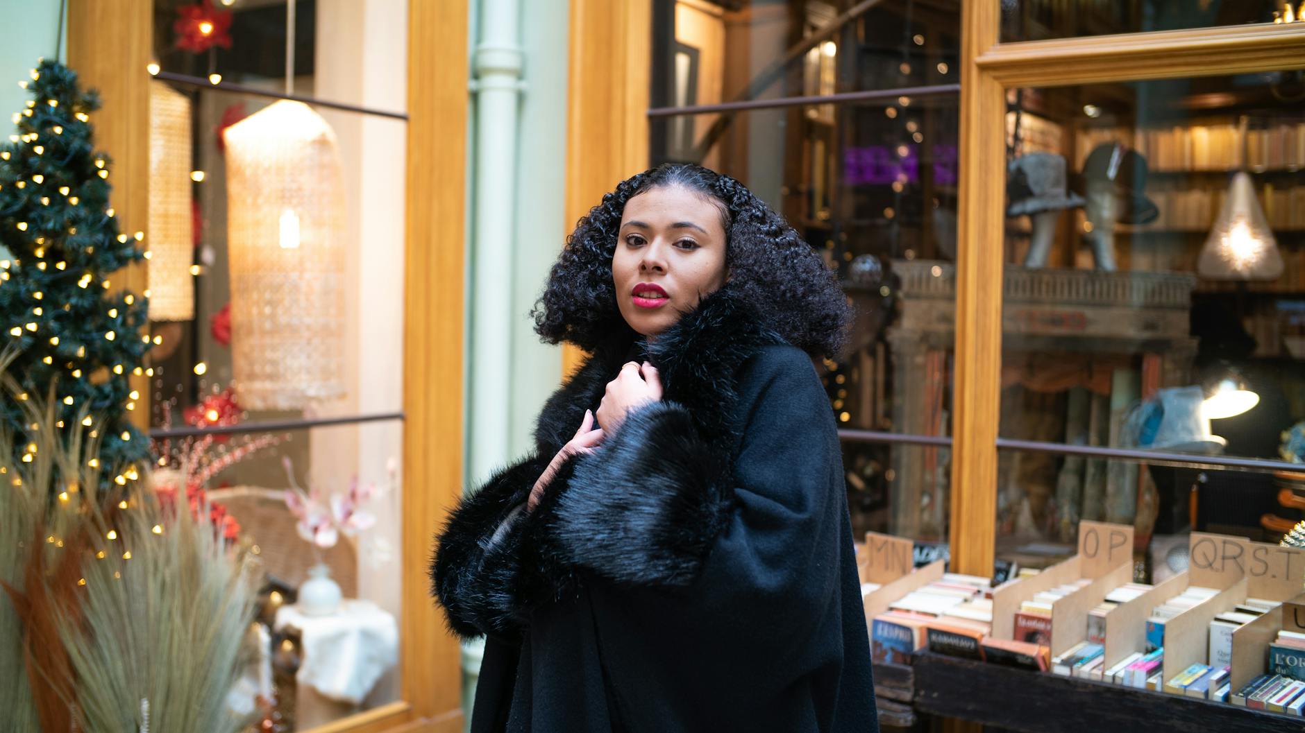 Kobieta w czarnym futrzanym płaszczu w przytulnej paryskiej księgarni