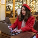 Kobieta w czerwonym francuskim płaszczu pracuje w paryskiej kawiarni