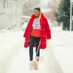 Kobieta w czerwonym płaszczu idąca pewnie po ośnieżonej ulicy