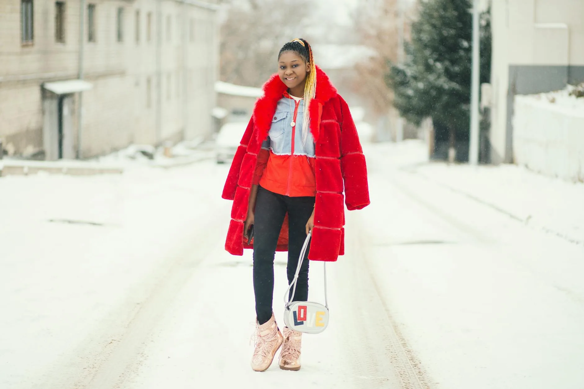Kobieta w czerwonym płaszczu idąca pewnie po ośnieżonej ulicy