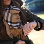 Kobieta w jesiennej stylizacji warstwowej sprawdza godzinę na zegarku