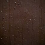 Krople deszczu na brązowej powierzchni w zbliżeniu