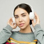 Młoda kobieta w słuchawkach w casualowym stroju warstwowym w domu