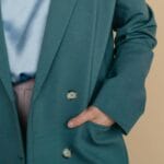 Zbliżenie na kobietę w efektownym zielonym płaszczu z rękami w kieszeniach