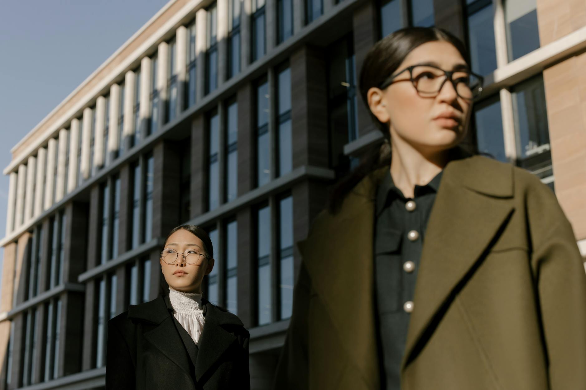 Dwie Azjatki w modnych płaszczach dwurzędowych na miejskim spacerze