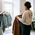 Kobieta ogląda płaszcze na wieszaku w przytulnym sklepie