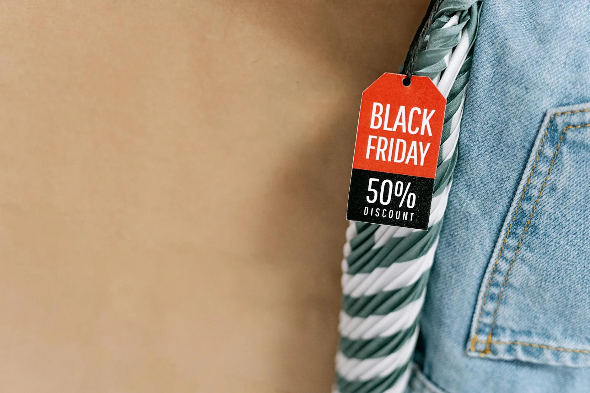 Metka Black Friday -50% na dżinsie i uchwyt torby na brązowym tle