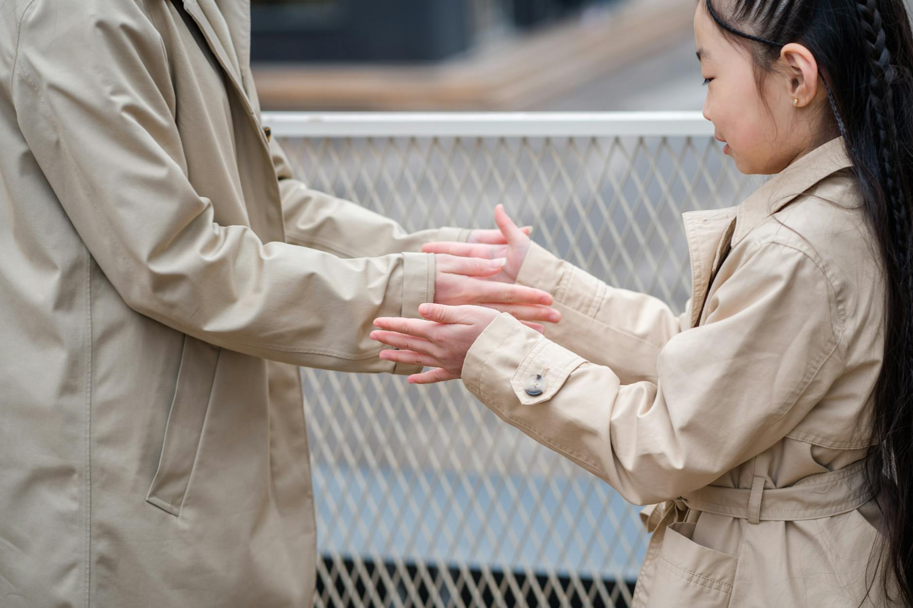 Ponadczasowy beżowy trencz: jak wystylizować go na sportowo i elegancko Młoda kobieta w beżowym trenczu bawiąca się na świeżym powietrzu