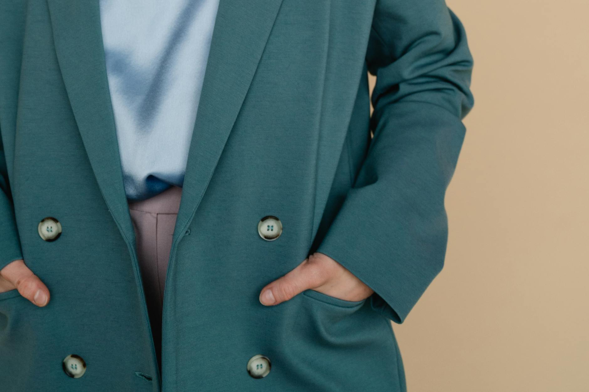 Zbliżenie na kobietę w modnym zielonym płaszczu z rękami w kieszeniach