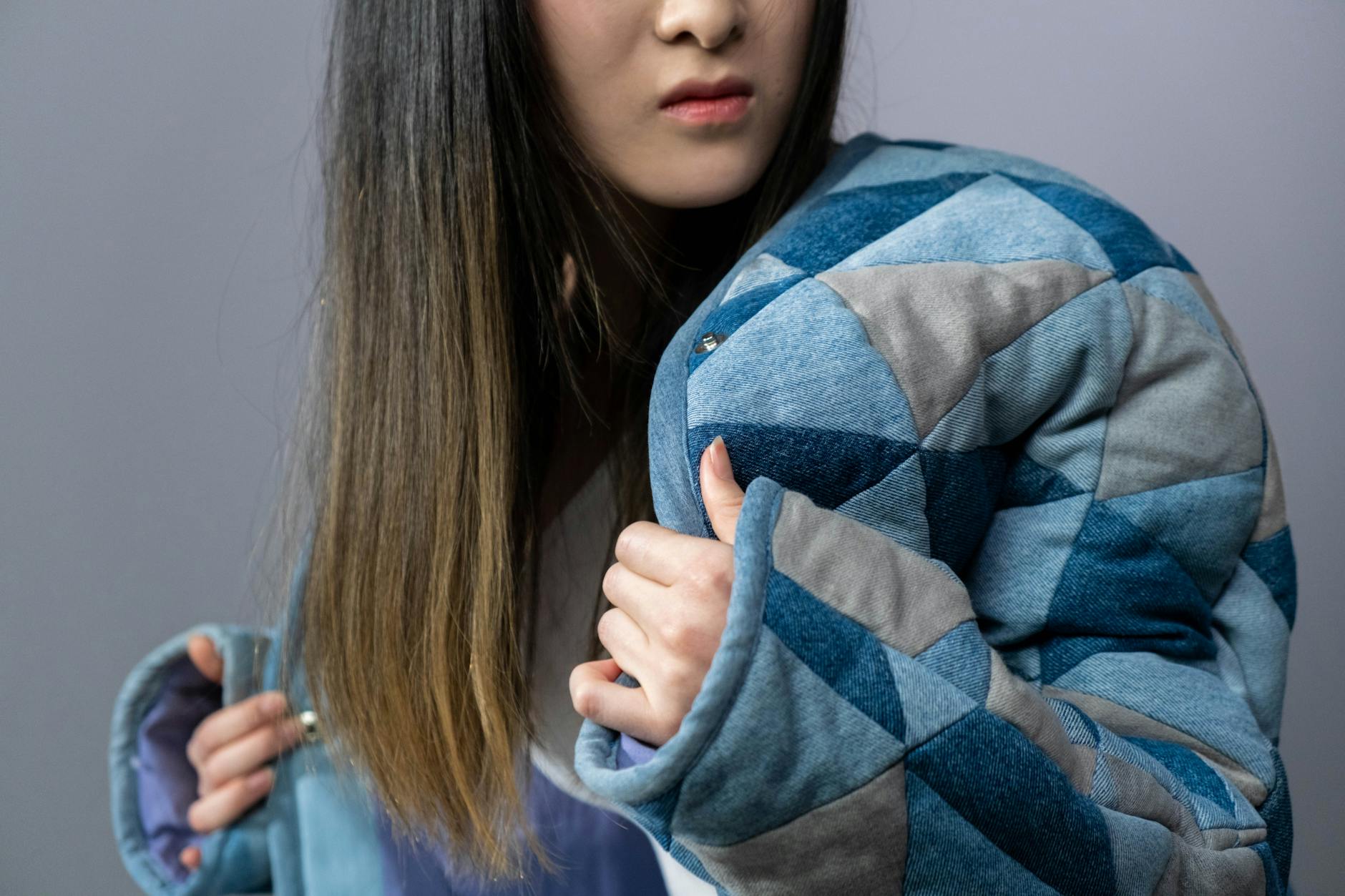 Kobieta w dżinsowej kurtce pozuje na szarym tle studio