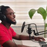 Mężczyzna przy biurku nagrywa podcast na mikrofonie w domowym biurze