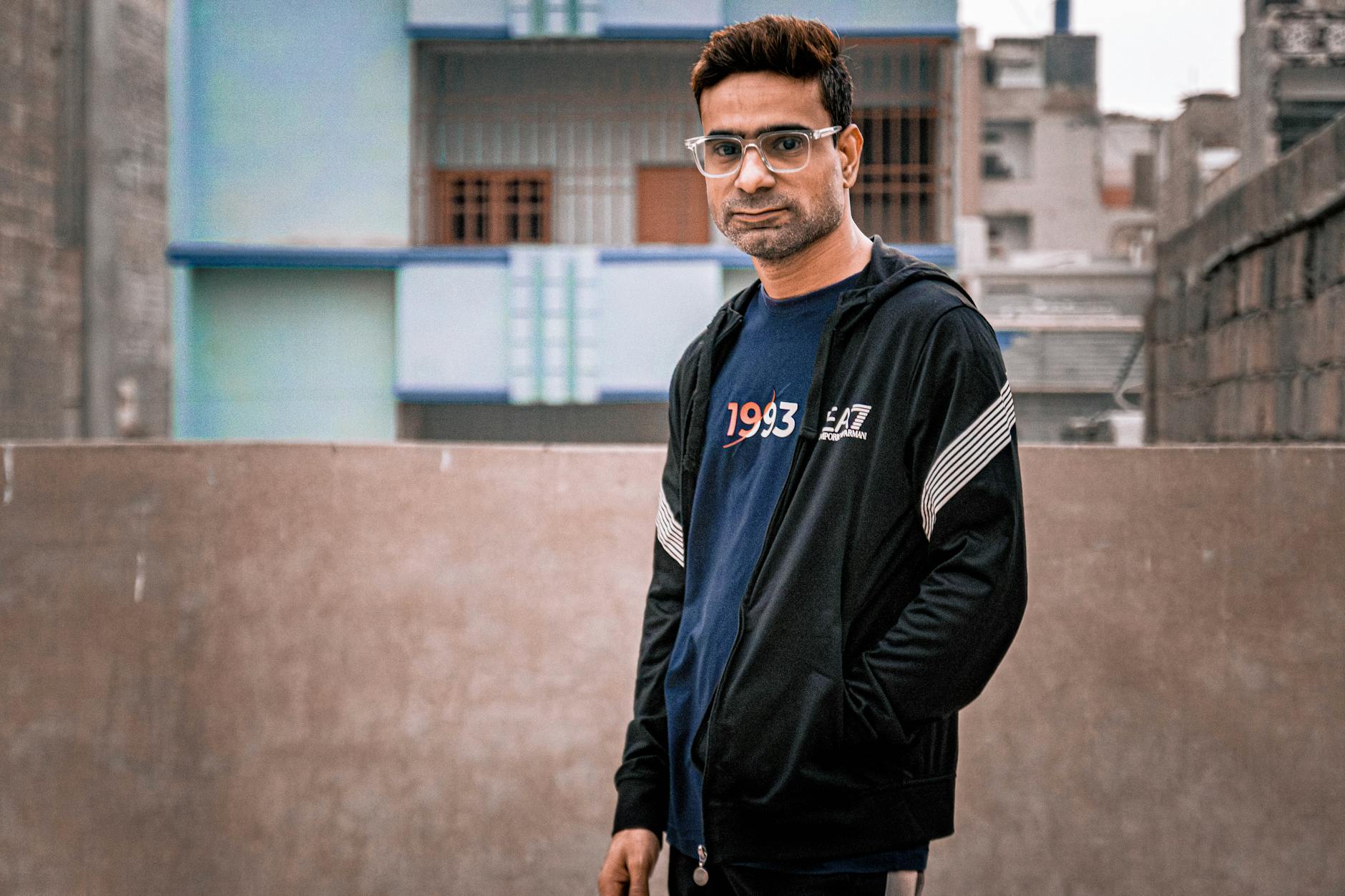 Mężczyzna w dresie i okularach na miejskim dachu