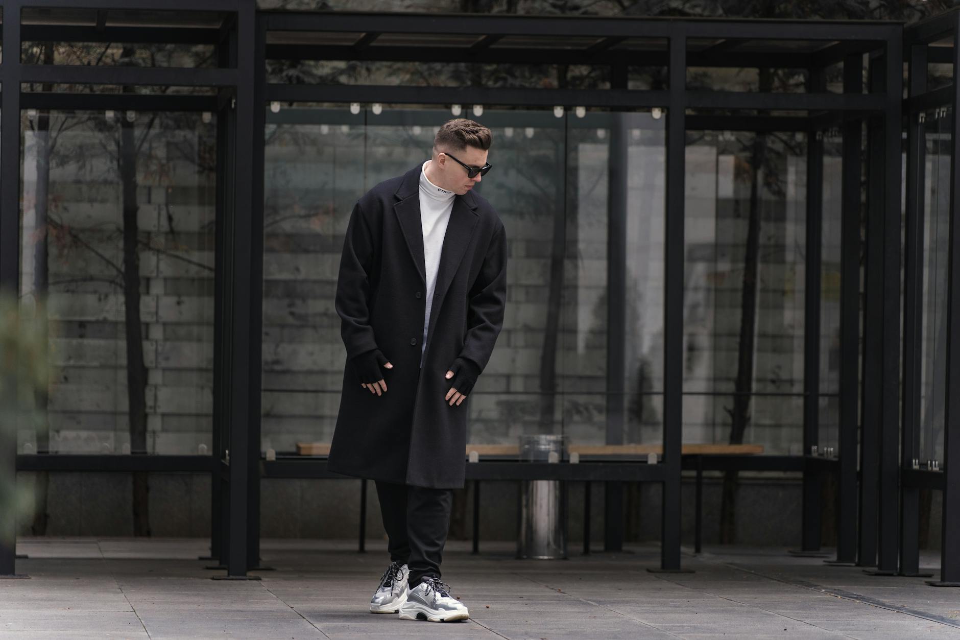 Mężczyzna w oversize’owym płaszczu streetwear pozuje na ulicy