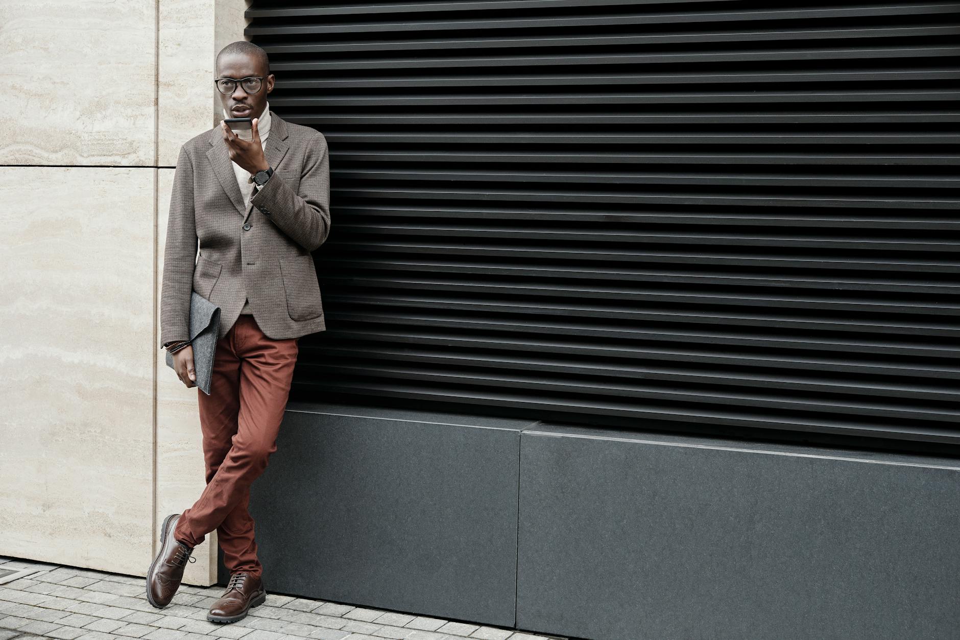 Jak dobrać kurtkę męską do butów: sneakersy, trzewiki, sztyblety i eleganckie derby Stylowy mężczyzna w smart casual w kurtce rozmawia przez telefon na zewnątrz