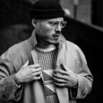 Stylowy mężczyzna w trenczu i okularach w czarno-białym ujęciu