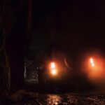 Pojazd terenowy z włączonymi reflektorami w ciemnym tunelu górniczym