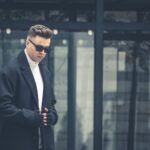 Mężczyzna w ciemnym płaszczu i okularach przeciwsłonecznych na zewnątrz